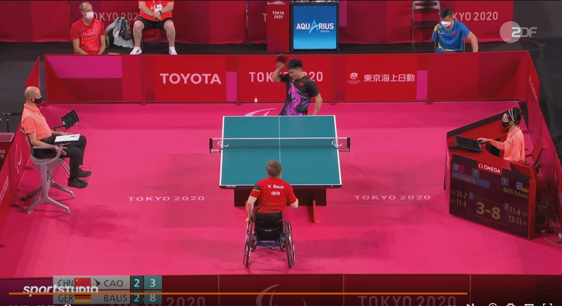 Still aus dem Film: Spielszene aus dem Tischtennis-Finale der Paralympics in Tokio 2020. Valentin Baus (vorne im roten Trikot) gewinnt gegen Cao aus China (hinten im schwarzen Trikot) - Spielstand im fünften Satz: 8:3 für Baus